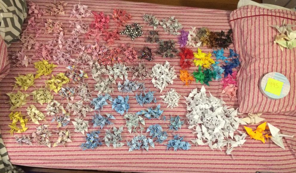 995 cranes of various colours lined on a bed