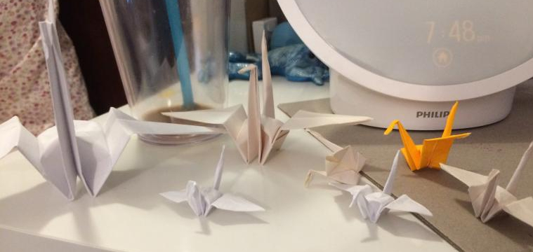 seven cranes of various material and sizes on a desk