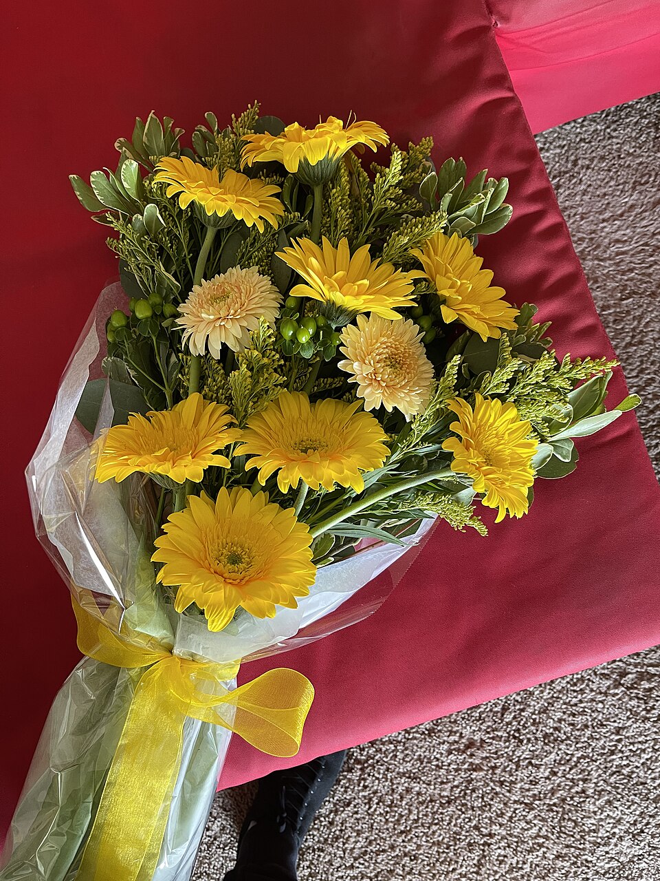 A beautiful arranged bouquet of yellow flowers secured with a bright yellow ribbon.