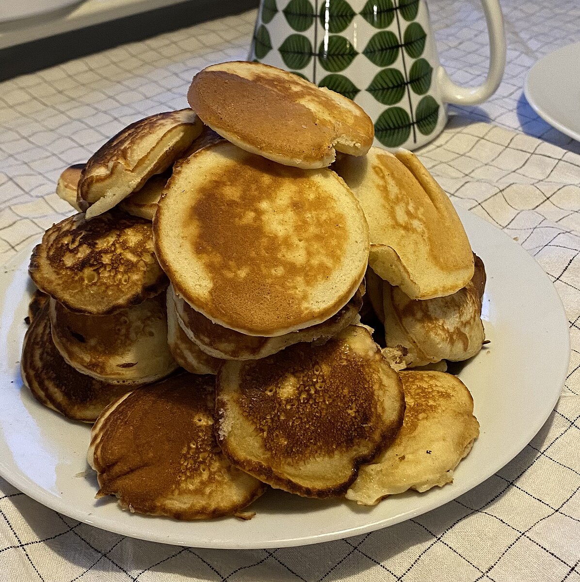 A towering plate of dime pancakes heaped until no more can physically be added.
