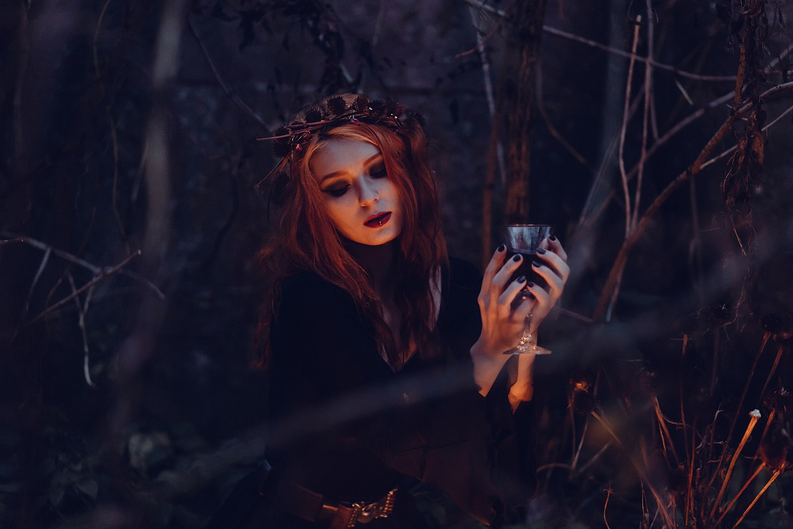A modern witch conducts a ritual in the forest at night.